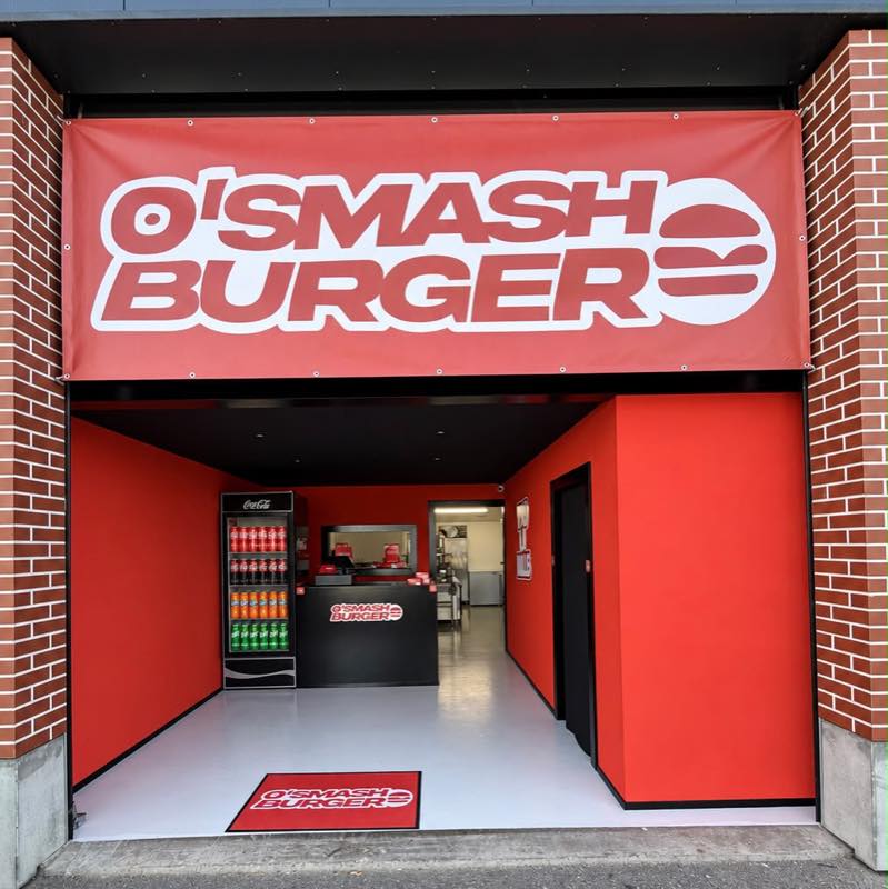 L'entrée de la dark kitchen O'SMASH BURGER à Payerne : bâche rouge au nom de l'enseigne au-dessus du comptoir.